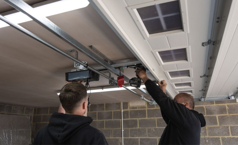 technicians installing struts on a garage door