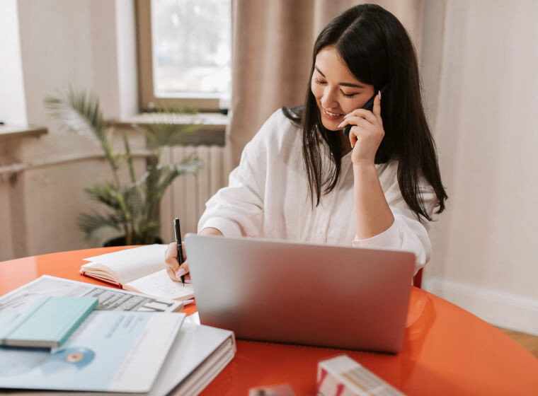 woman on the phone, sitting at her laptop